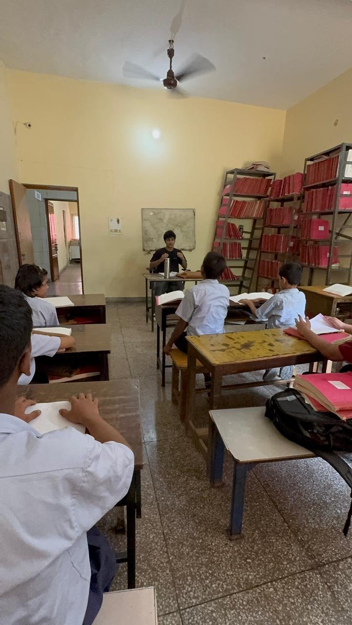 Leading a lesson from the front of the classroom as students follow along with their braille textbooks