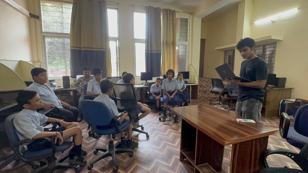Leading a workshop with students seated in a circle, reading from a laptop