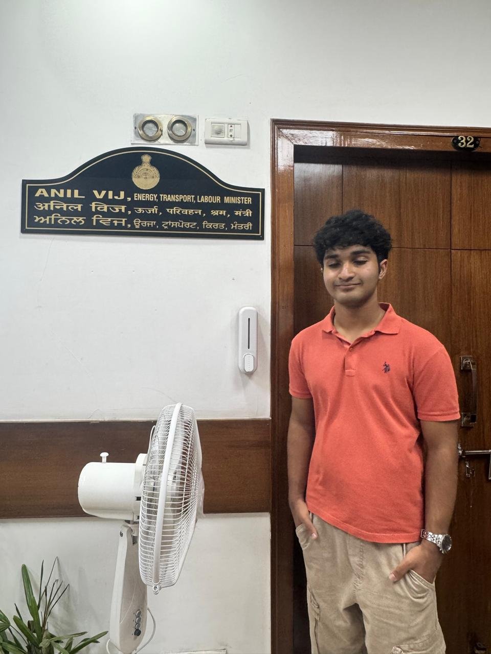 Standing outside Anil Vij's office door at the Haryana Secretariat, beside the nameplate reading Anil Vij, Energy, Transport, Labour Minister