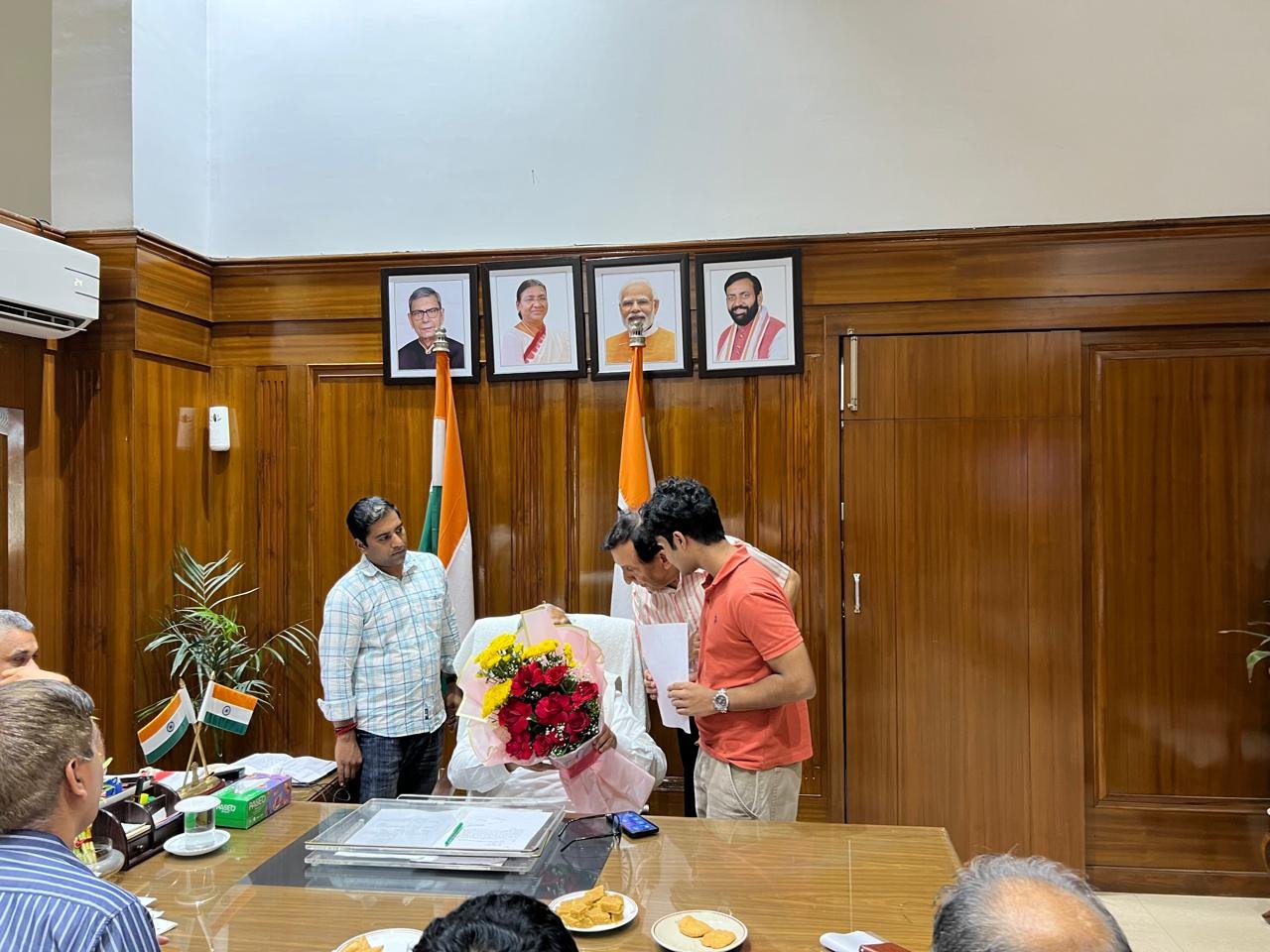 Anil Vij receiving the bouquet of flowers at his desk