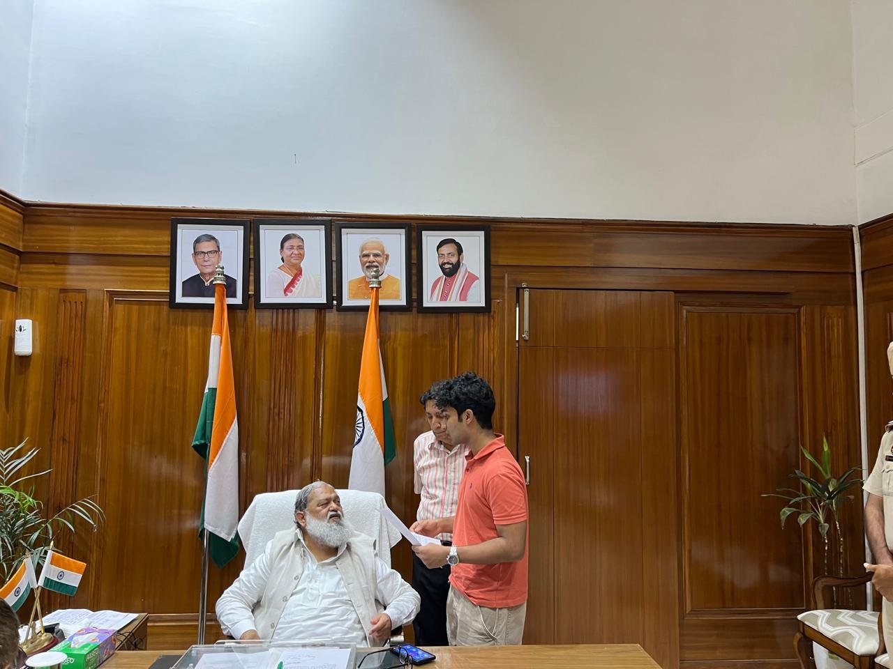 Anil Vij preparing to sign the accessibility petition as a police officer looks on