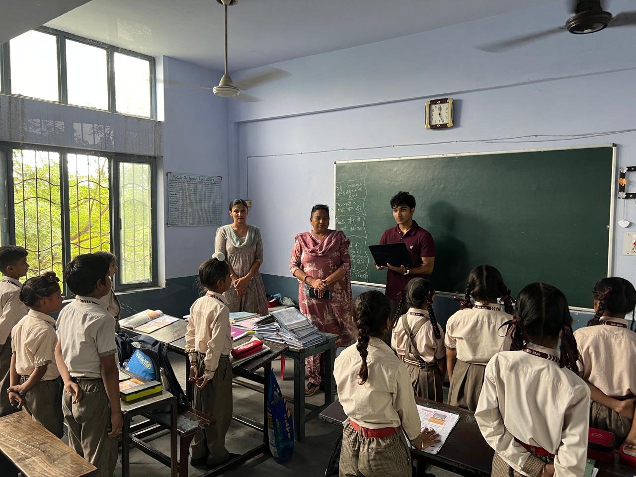 Students standing at their desks and listening as the workshop begins