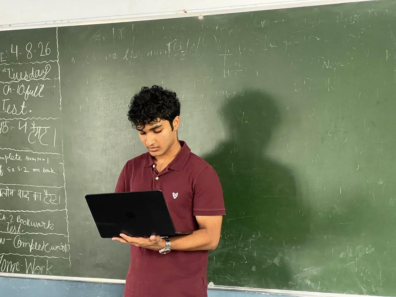 A portrait at the chalkboard, reviewing notes on a laptop before the next session